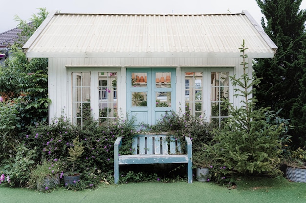 Белый деревянный дом Уютный маленький дом для развлечений с белыми и розовыми окнами и дверями Есть деревья вокруг сада