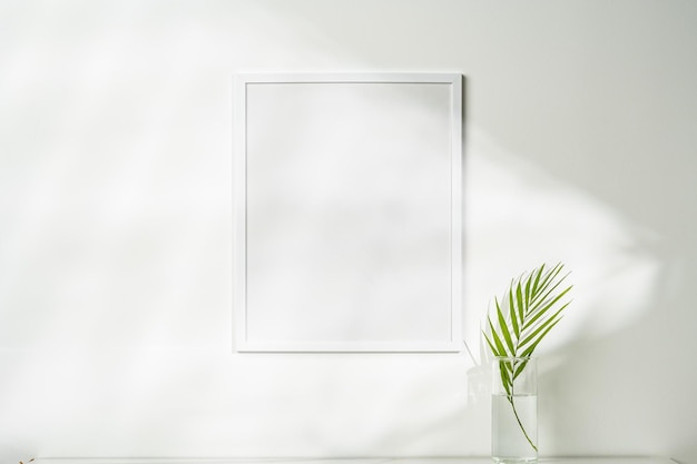Photo white wooden photo frame with plant leaves on white background