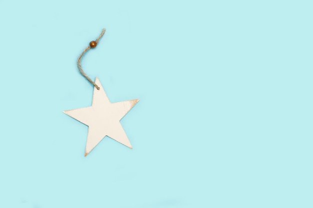 A white wooden star on a light blue background with copy space