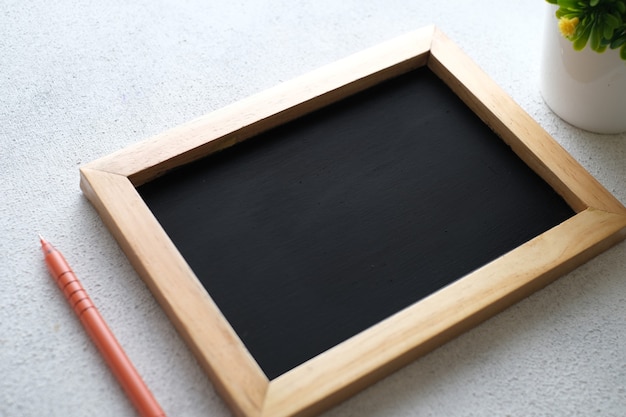 White wooden table with chalkboard, eyeglasses, pen, decorative plants. top view with copy space, flat lay.