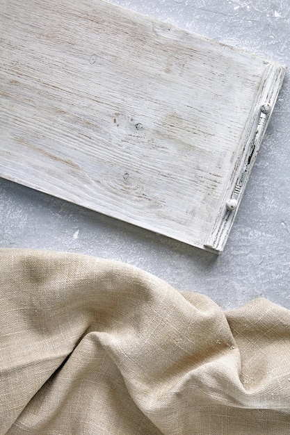 Foto un vassoio di legno bianco e un tovagliolo di lino grezzo su un tavolo di cemento grigio