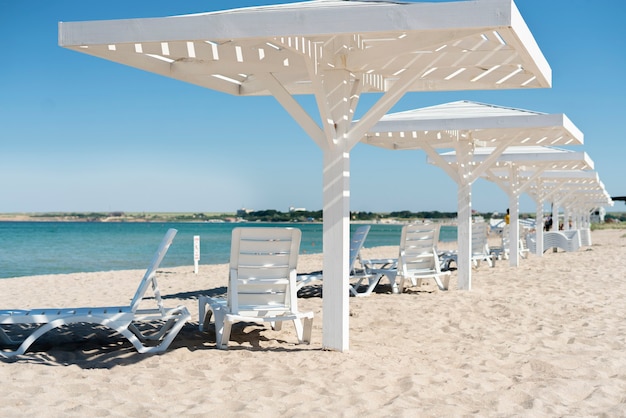 여름 모래 해변에 흰색 나무 우산. 목가적인 해안선 리조트