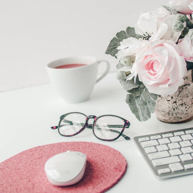 Photo white workspace with light pink note book and white flower with coffee on white table