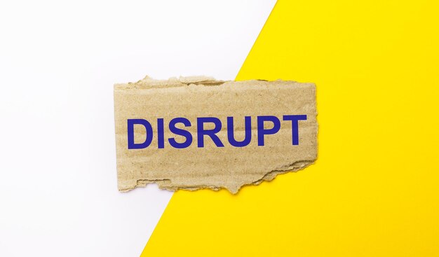 白と黄色の背景に、茶色の破れた段ボールに「DISRUPT」というテキストが表示されます