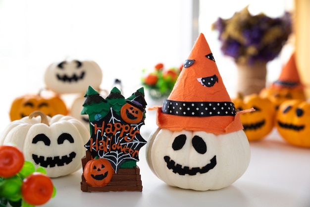 White and yellow ghost pumpkins with witch hat and Happy halloween text on board