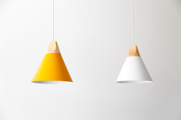 Photo white and yellow lamps with light wooden parts are hanging on the cables