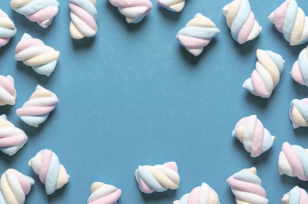 White, yellow, pink, and light blue marshmallows on light blue background.