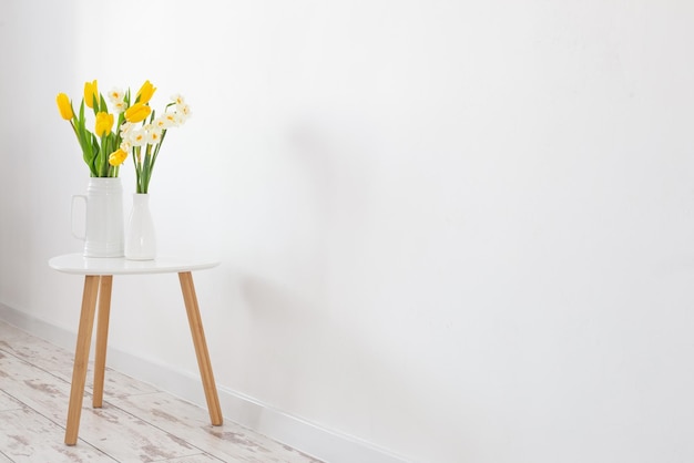 White and yellow spring flowers in vase on white background