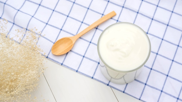 White yogurt and spoon on a wooden table.