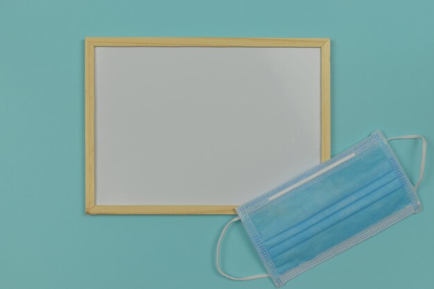 Whiteboard with medical mask on blue