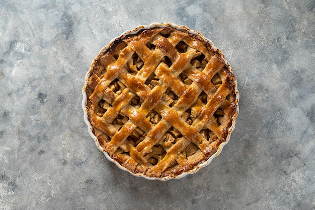 Whole apple pie in white ceramic baking pan top view