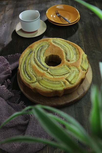 Foto pan di spagna alla banana intera con banana affettata su un tavolo di legno