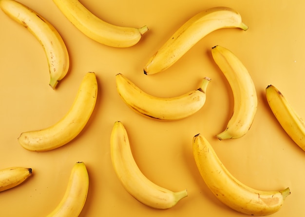 Whole bananas with peel on yellow surface