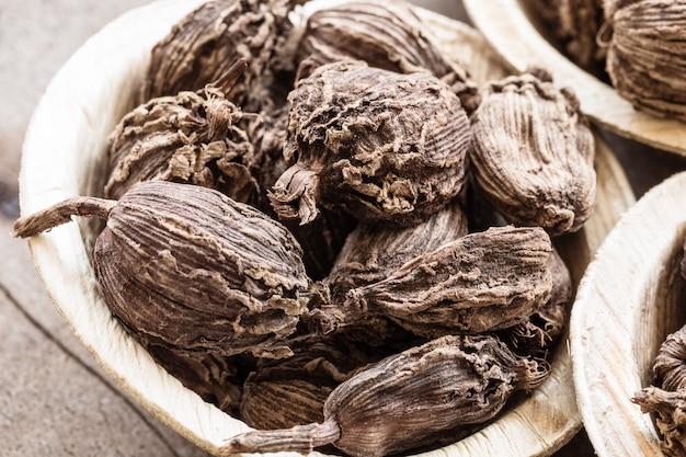 Whole black cardamom in a bowl on wood