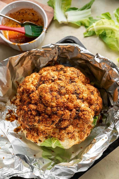 Whole cauliflower head with herbs and spices Cooking process of roasted cauliflower top view