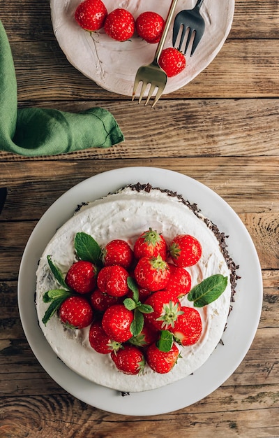 Whole chocolate mousse cake with strawberry and mint over wooden rustic background Top view