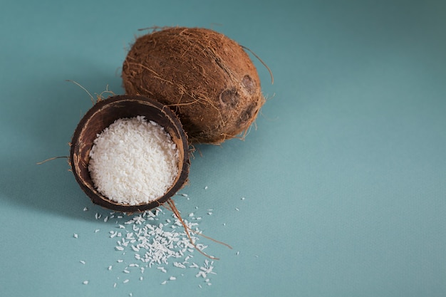 Whole coconut with coconuts flakes on a blue