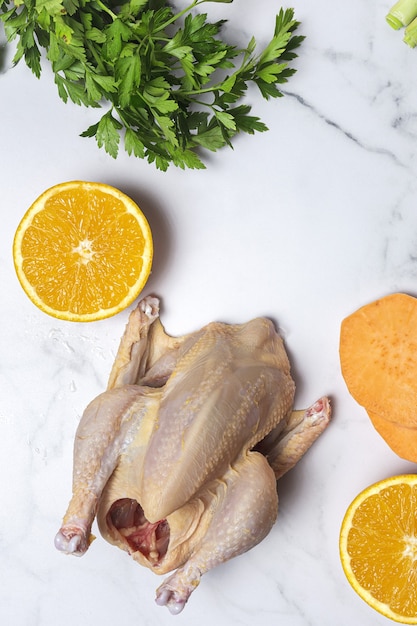 Whole coquelet chickens with raw vegetables ready to cook