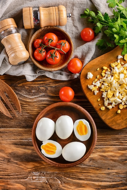 Whole and cut boiled eggs with spices on wooden table