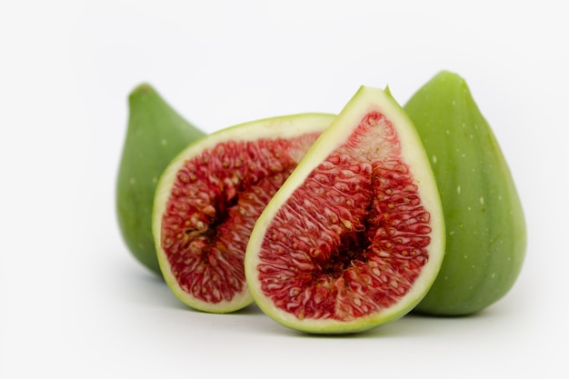 Whole and cut green figs on white background