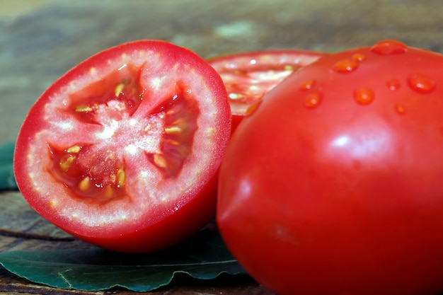 Pomodori interi e tagliati su fondo di legno