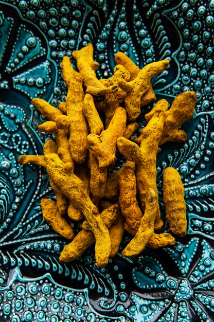 Whole dry turmeric roots on ceramic plate