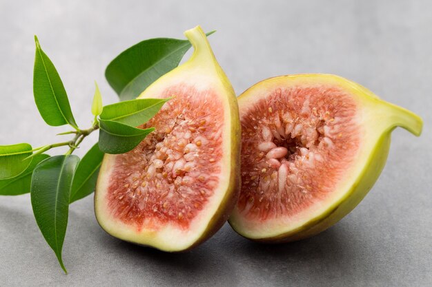 Whole figs and one fig sliced in half on top of a gray table.