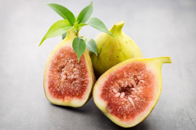 Whole figs and one fig sliced in half on top of a gray table