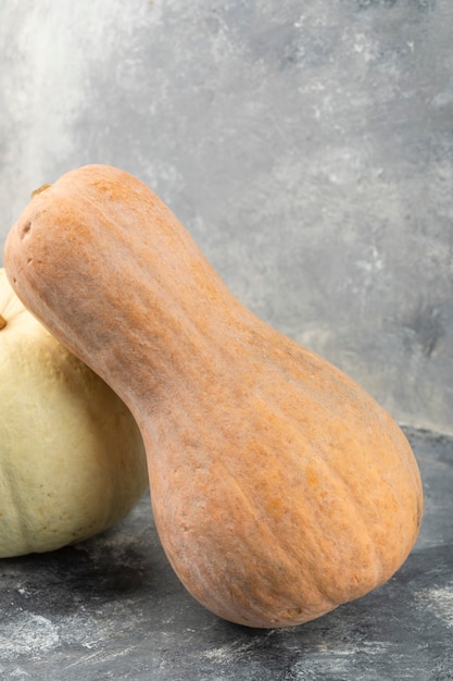 Whole fresh grey pumpkin with butternut squash placed on a marble table . 