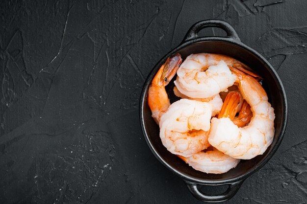 Photo whole fresh peeled cooked prawns, shrimps set, in bowl, on black background, top view flat lay , with copyspace  and space for text