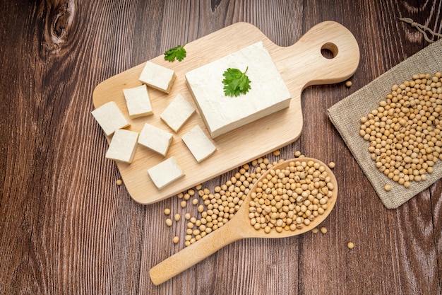 Foto tofu fresco intero in piatto bianco e tofu a dadi in piatto su fondo di legno cibo vegano sano