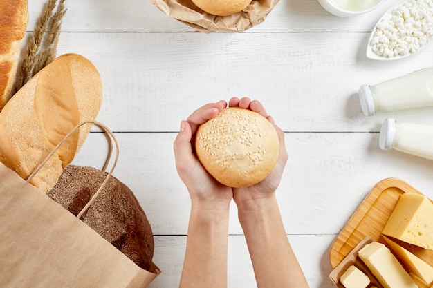 Whole grain bread in ecology paper bag on white wooden background