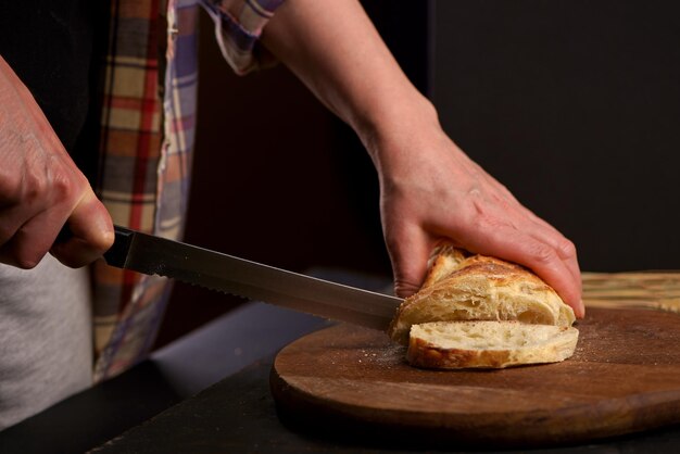 Whole grain bread put on kitchen wood plate with a chef holding knife for cut