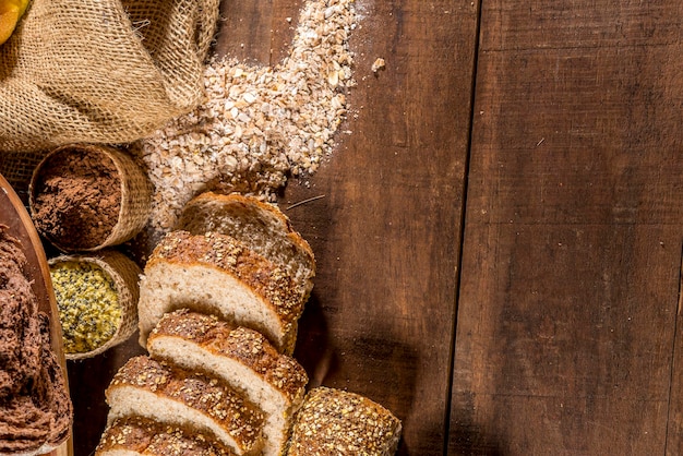 Whole grain bread on rustic wooden table with ingredients in background top view copy space