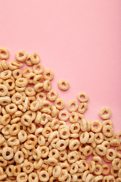 Whole grain cereal rings on pink background Vertical photo