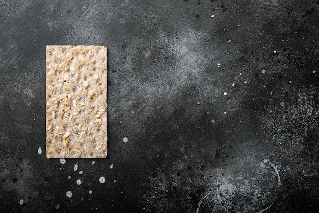 Whole grain crisp bread set, on black dark stone table background, top view flat lay, with copy space for text