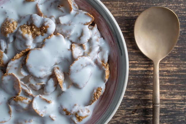 Whole grain glazed flakes with yogurt in plate, close up, top view.