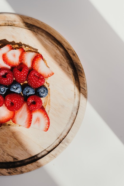 Whole grain toast with peanut butter strawberry and raspberry on wooden board