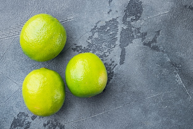 Whole green lime set, on gray table, top view or flat lay