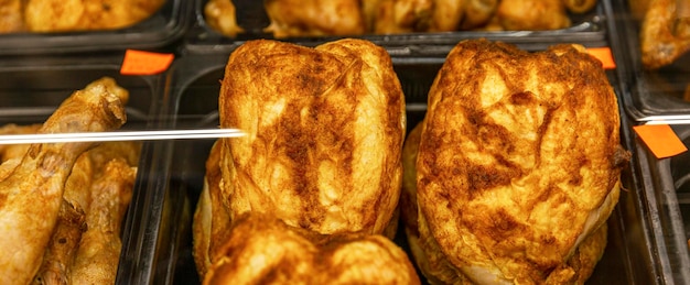 Whole grilled fried chicken with a delicious crust on the counter in the store Fast delicious unhealthy food Closeup Panorama format