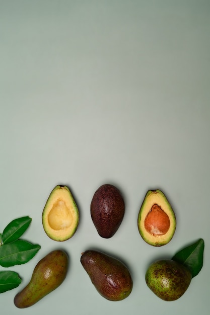 Whole and half avocado on green background.