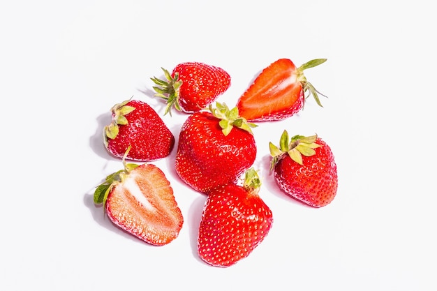 Whole and half ripe strawberry isolated on white background. Sweet fresh summer fruit, healthy food. A modern hard light, dark shadow, top view