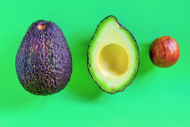 whole and halved avocado isolated on green