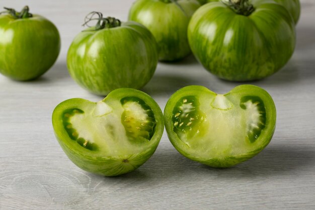 Whole and halved fresh green zebra tomato close up