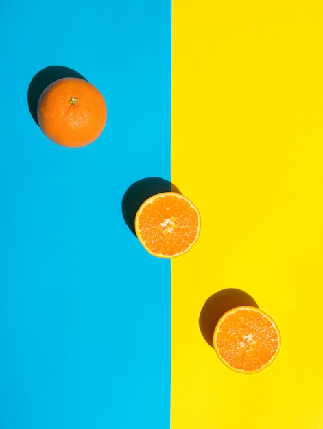 Photo whole and halved  orange on vivid duotone blue yellow background arranged in diagonal.