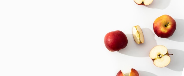 Целые половинки и нарезанные яблоки на белом фоне Вид сверху плоский баннер