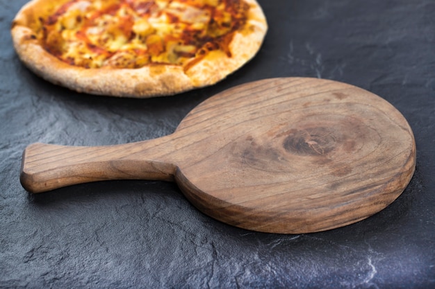 Whole hot delicious pizza placed on a wooden cutting board . 