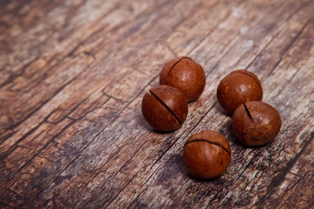 Noci di macadamia intere sul fondo di legno strutturato della tavola. vista frontale e dall'alto, primo piano. spazio di copyright per il sito web o il logo