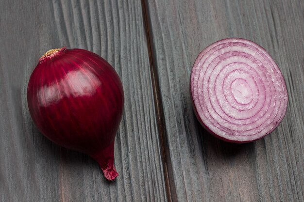 Whole onion and half an onion. Purple onion. Dark wooden background. Top view