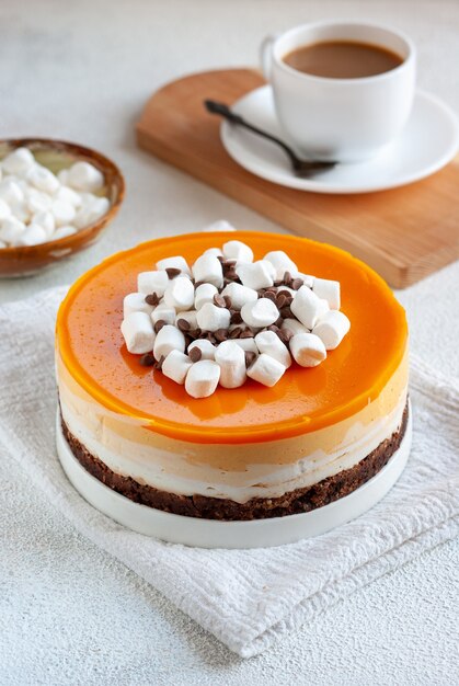 Whole orange cheesecake with chocolate, marshmallow and cup of coffee